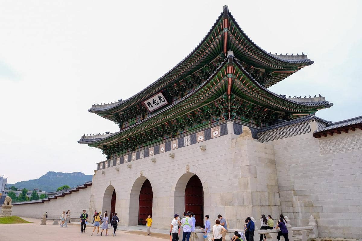 Kompleks Istana Gyeongbokgung di Seoul dengan bangunan tradisional beratap melengkung dan halaman luas di bawah langit cerah.