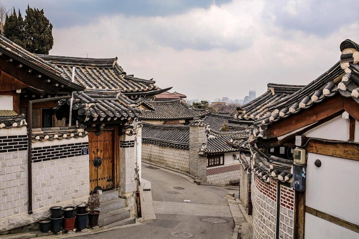 Deretan atap rumah hanok tradisional di Bukchon Hanok Village berpadu dengan bangunan kota di kejauhan.
