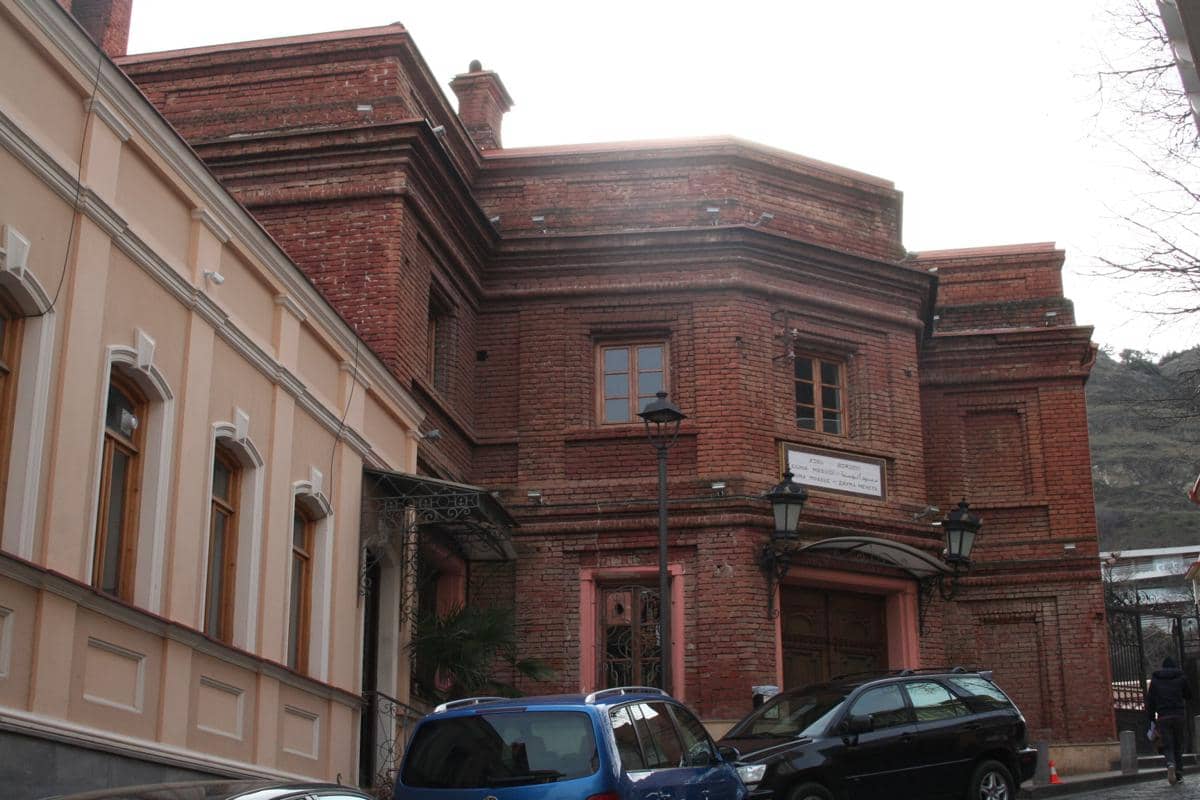 Pintu masuk Masjid Juma di Tbilisi dengan fasad bata, lengkungan dekoratif, dan menara di sisi bangunan.