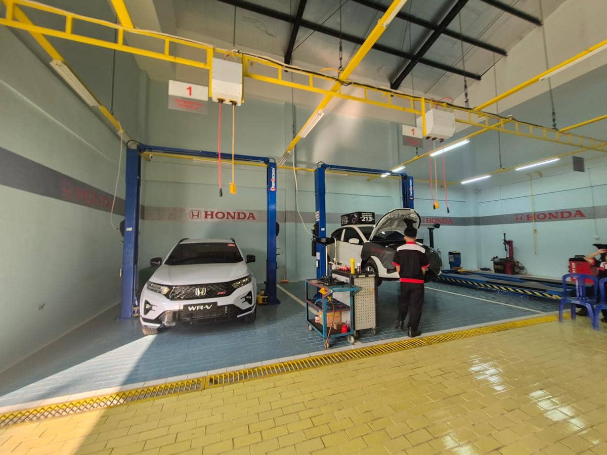 Sejumlah teknisi memeriksa dan melakukan perawatan mobil di area servis diler Honda yang dilengkapi peralatan bengkel.