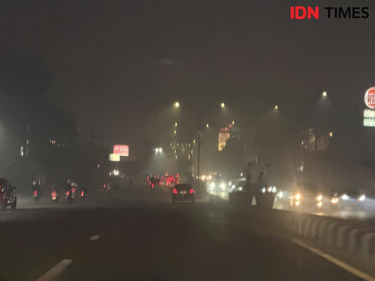 Kabut asap tebal menyelimuti Kota Palembang, membatasi jarak pandang dan membuat suasana perkotaan tampak berkabut.