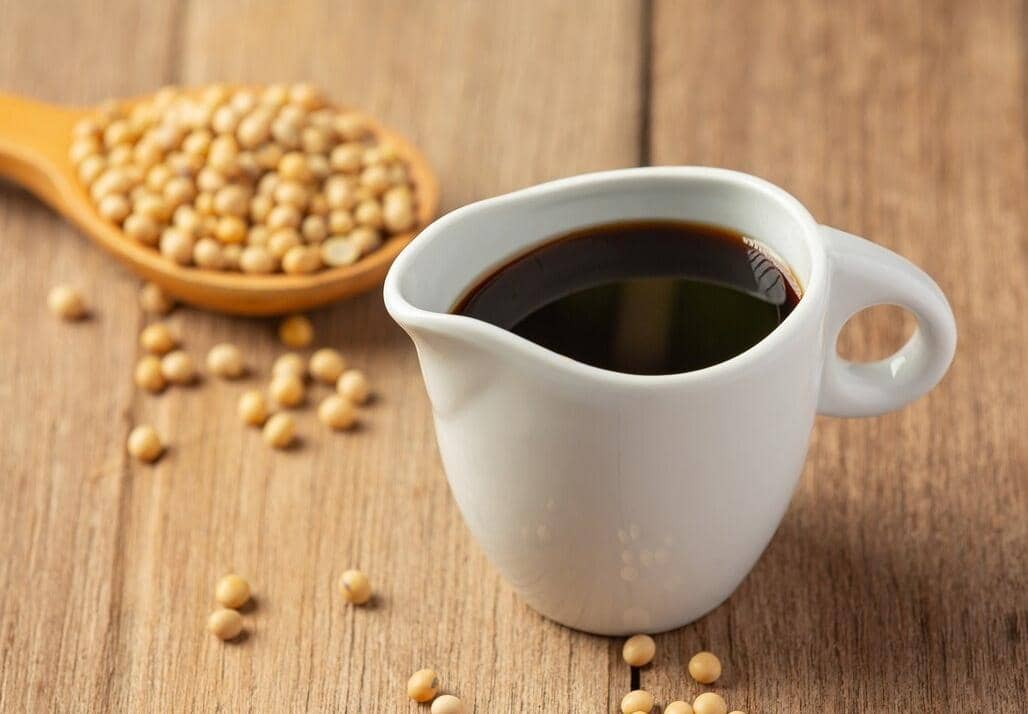 Ilustrasi kecap berwarna gelap sebagai pelengkap masakan, menggambarkan produk bumbu cair dengan desain sederhana.