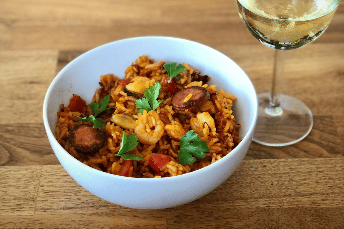 Semangkuk italian sausage orzo dengan pasta berbentuk beras, sosis, dan saus tomat sebagai ilustrasi hidangan.