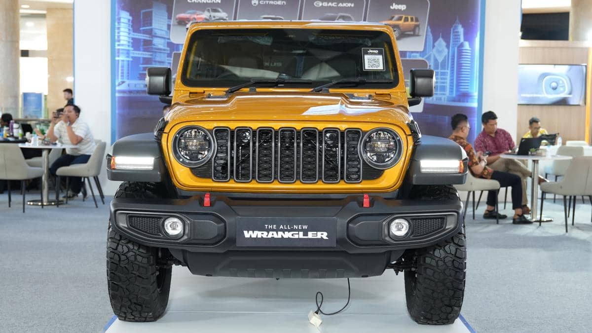 Jeep Wrangler berwarna emas diparkir di area terbuka, menonjolkan kilau cat Goldilocks dengan nuansa keemasan.