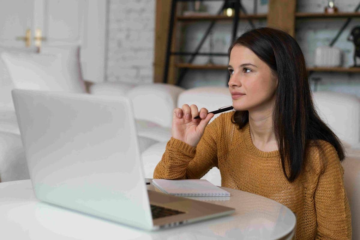 Seorang perempuan muda bekerja dengan laptop di meja, menggambarkan upaya mengingat kembali motivasi.
