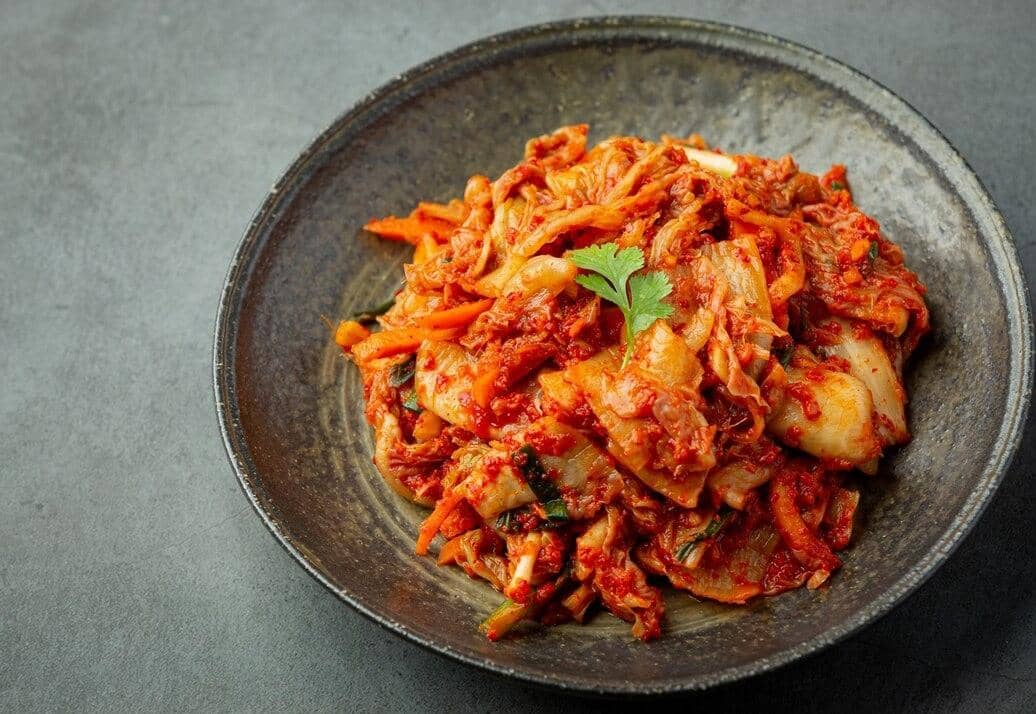 Ilustrasi kimchi, hidangan fermentasi khas Korea berbahan sayuran berbumbu merah yang kerap disajikan sebagai pelengkap.