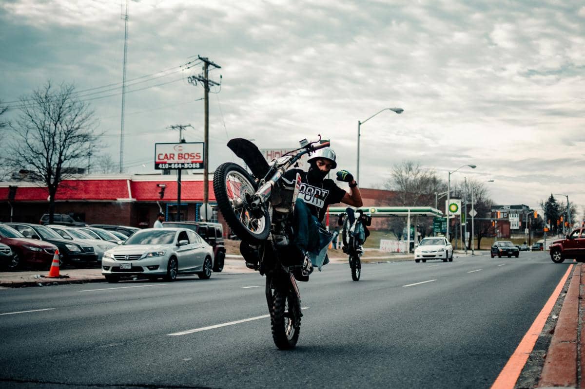 Ilustrasi seseorang melakukan Wheelie di jalan raya.jpg