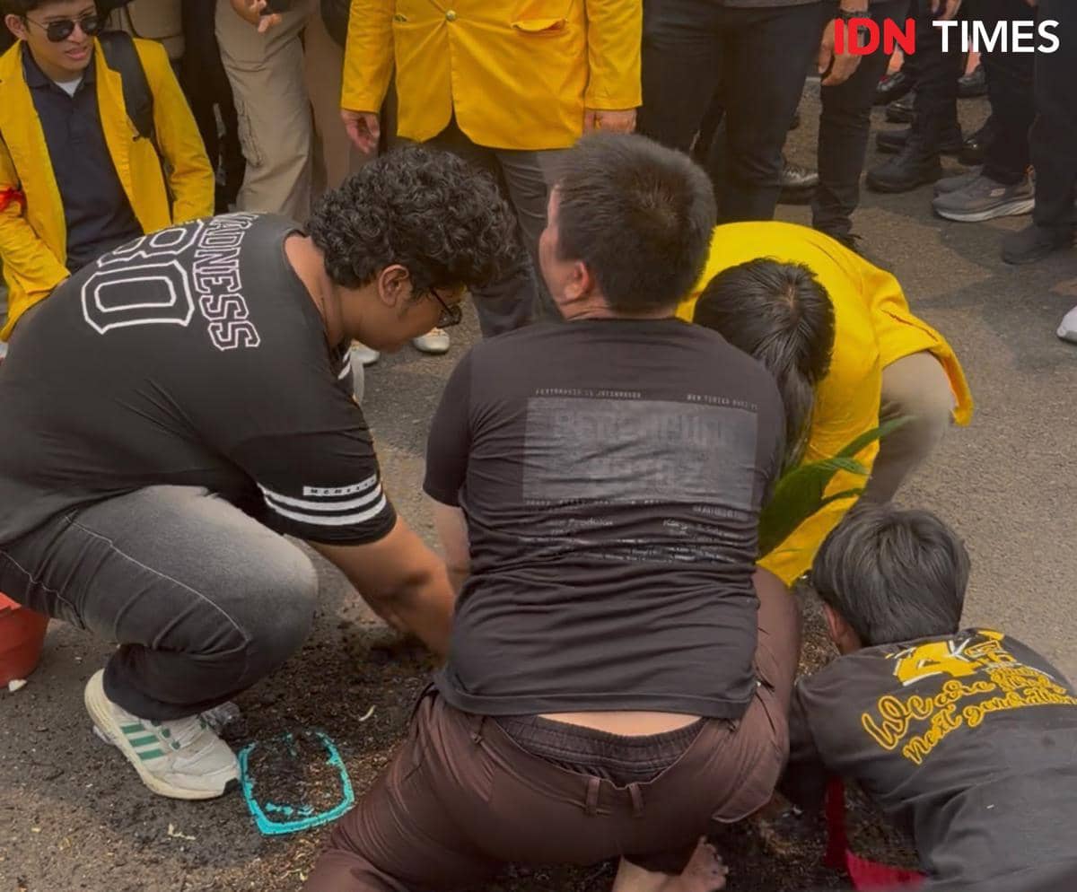 Peserta aksi teatrikal menanam sawit dan menyantap MBG di tengah kabut asap yang menyelimuti lokasi aksi.