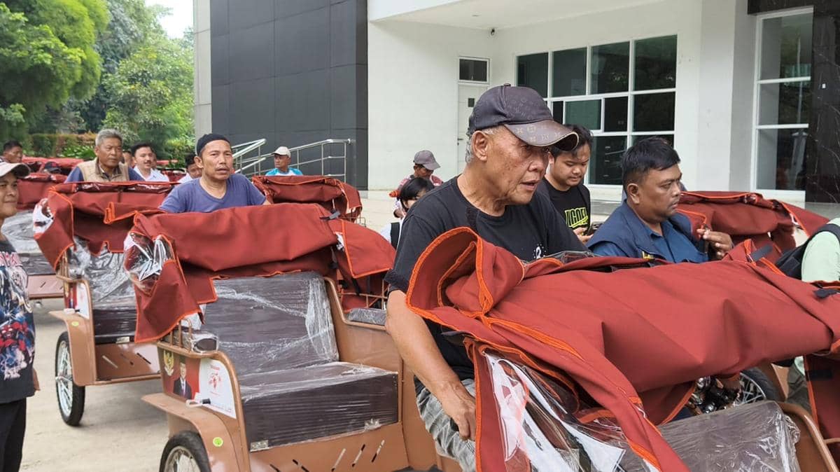 Seorang lansia pengayuh becak menerima becak listrik bantuan Presiden Prabowo di tengah kegiatan penyerahan.