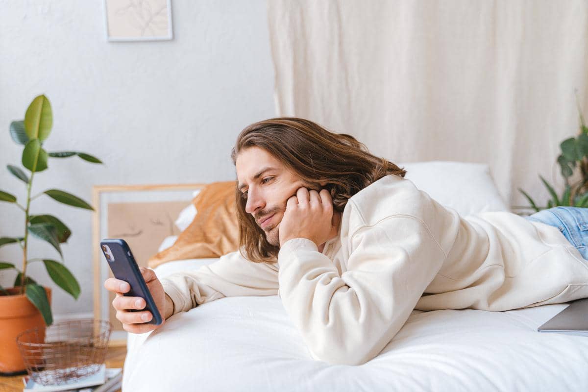 Seseorang menggunakan smartphone dalam suasana santai di kamar