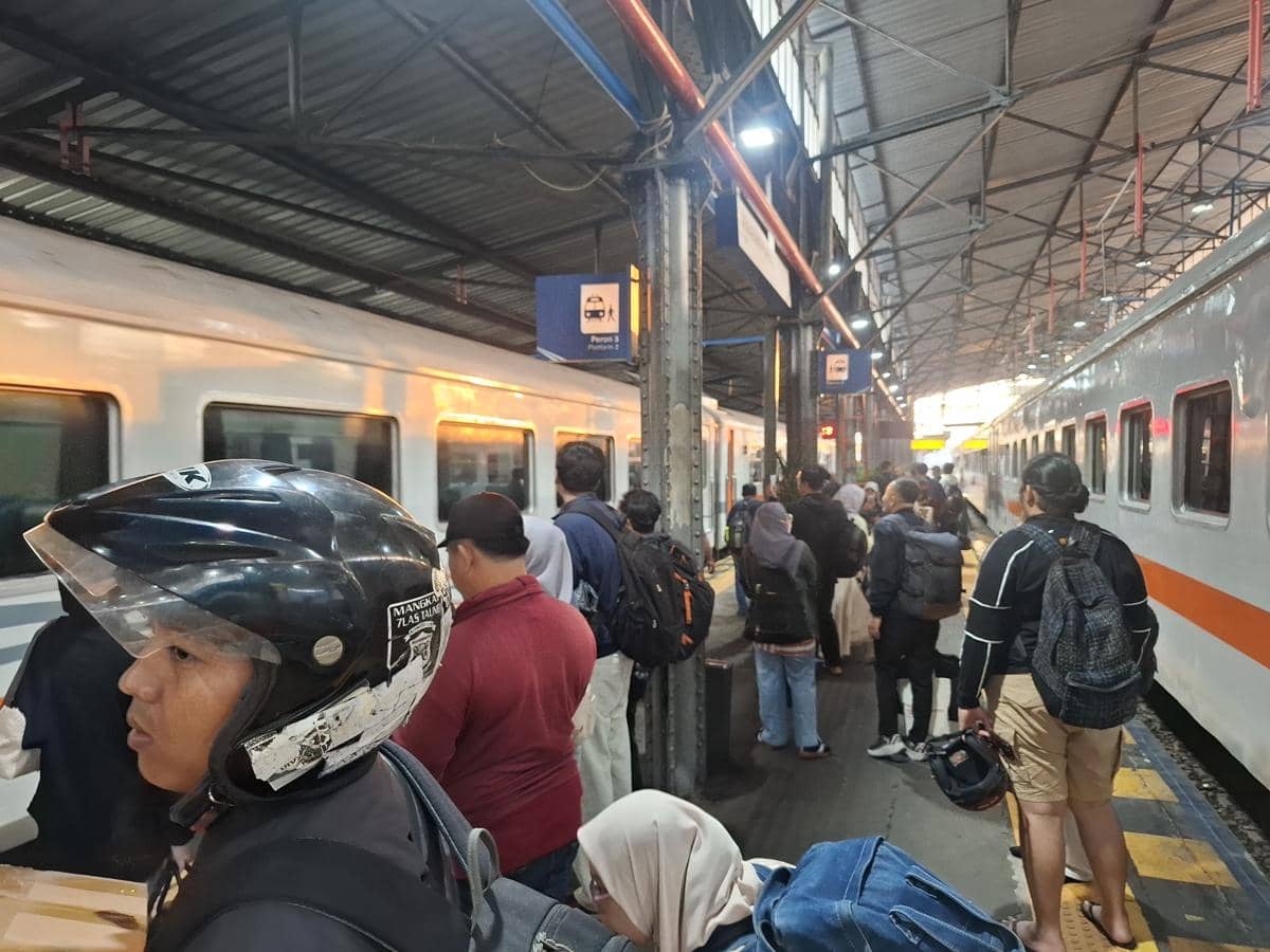 Sejumlah calon penumpang kereta api menunggu kedatangan kereta di selasar peron stasiun dengan barang bawaan mereka.