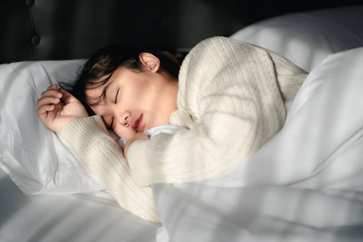 Ilustrasi seseorang tidur nyenyak di tempat tidur dengan suasana malam yang tenang dan nyaman.