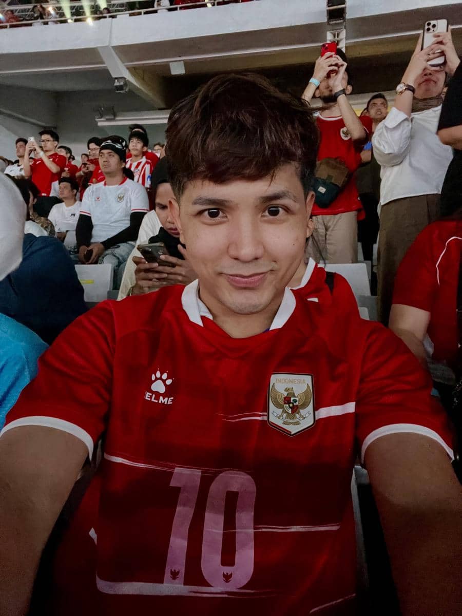 Jirayut duduk di tribun Stadion GBK menyaksikan pertandingan timnas Indonesia melawan Thailand bersama penonton.