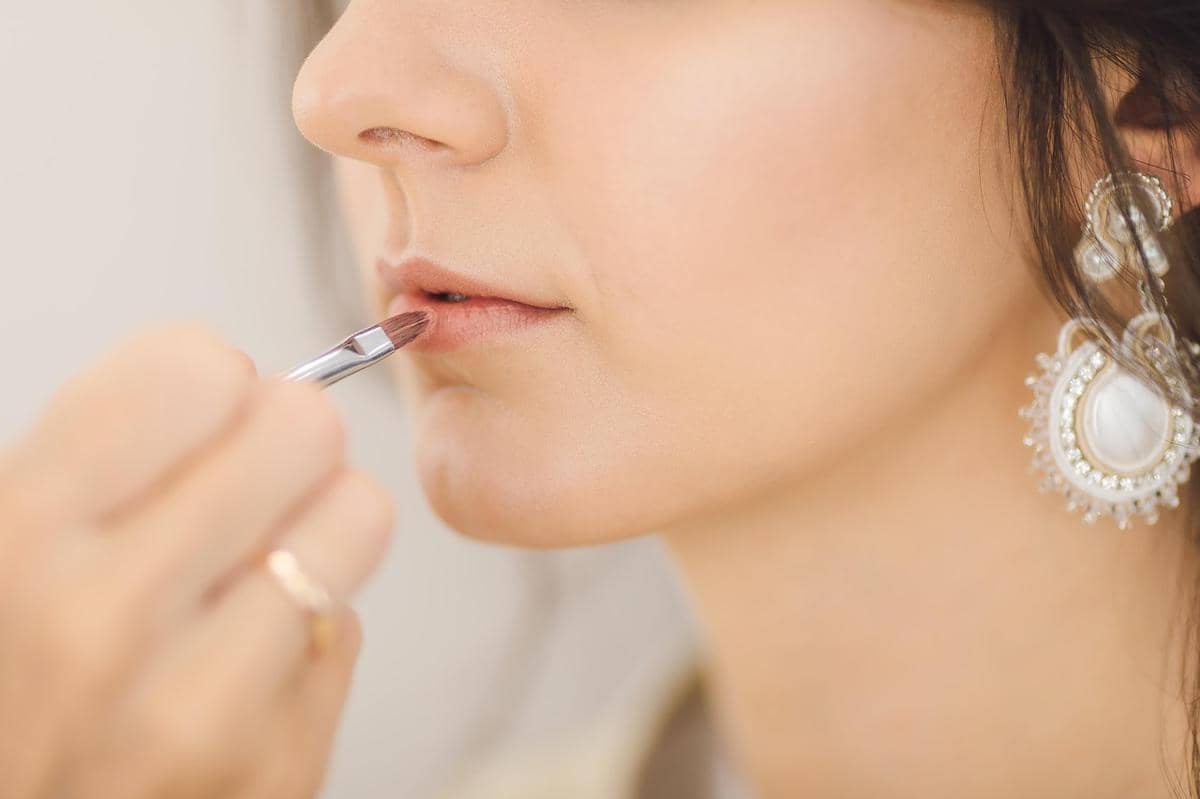mengaplikasikan lipstick ke bibir