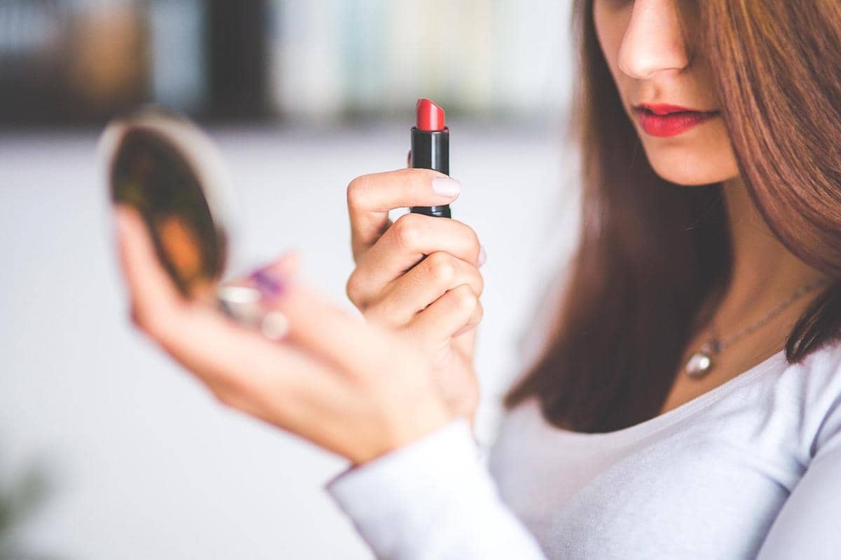 seorang wanita menggunakan lipstick