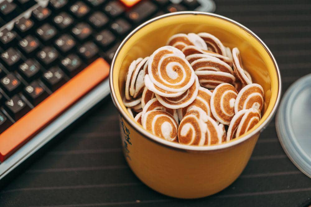 Toples berisi kue kuping gajah dengan pola spiral cokelat dan putih sebagai camilan rasa keju kopi.