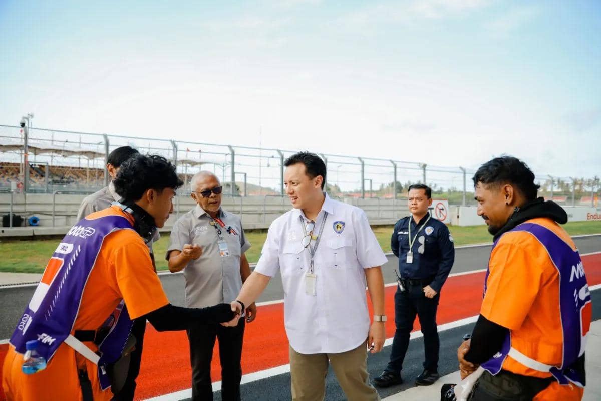 Ketua IMI Moreno Soeprapto bersalaman dan berdialog dengan petugas marshal berseragam oranye di tepi sirkuit