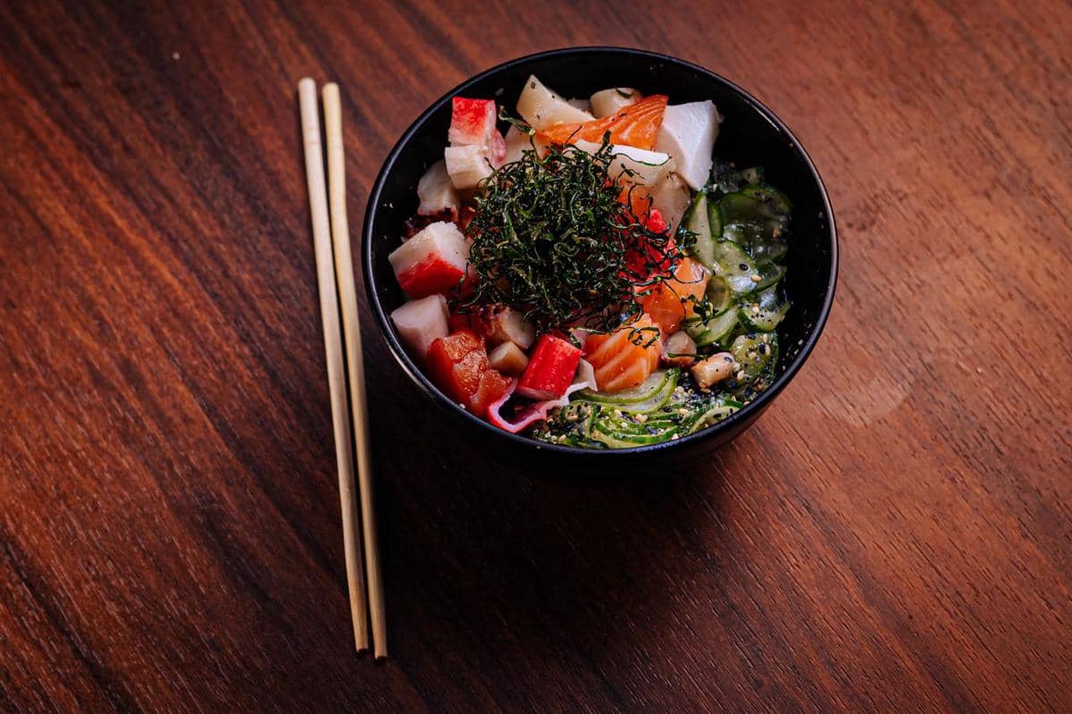 Semangkuk poke berisi nasi, ikan mentah, alpukat, edamame, dan sayuran segar sebagai hidangan sehat.