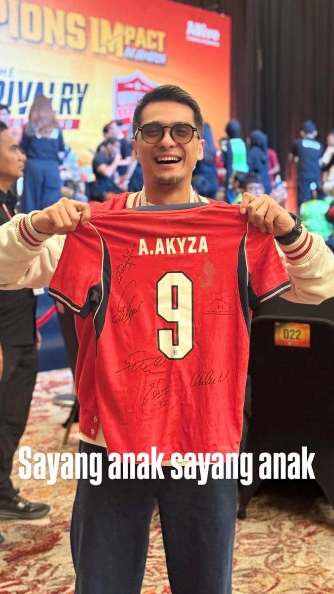 Seorang artis berpose bersama para pemain United Legends dan North London Legends di area pertandingan.