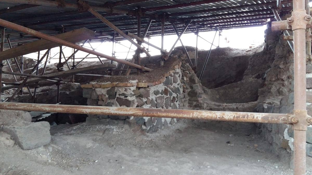 Pemandangan bagian dalam Kastel Alamut dengan struktur batu kuno dan area terbuka di antara reruntuhan bangunan.