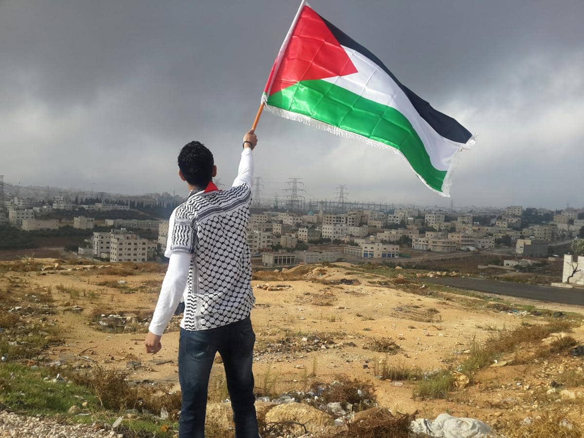 seorang pemuda mengibarkan bendera Palestina