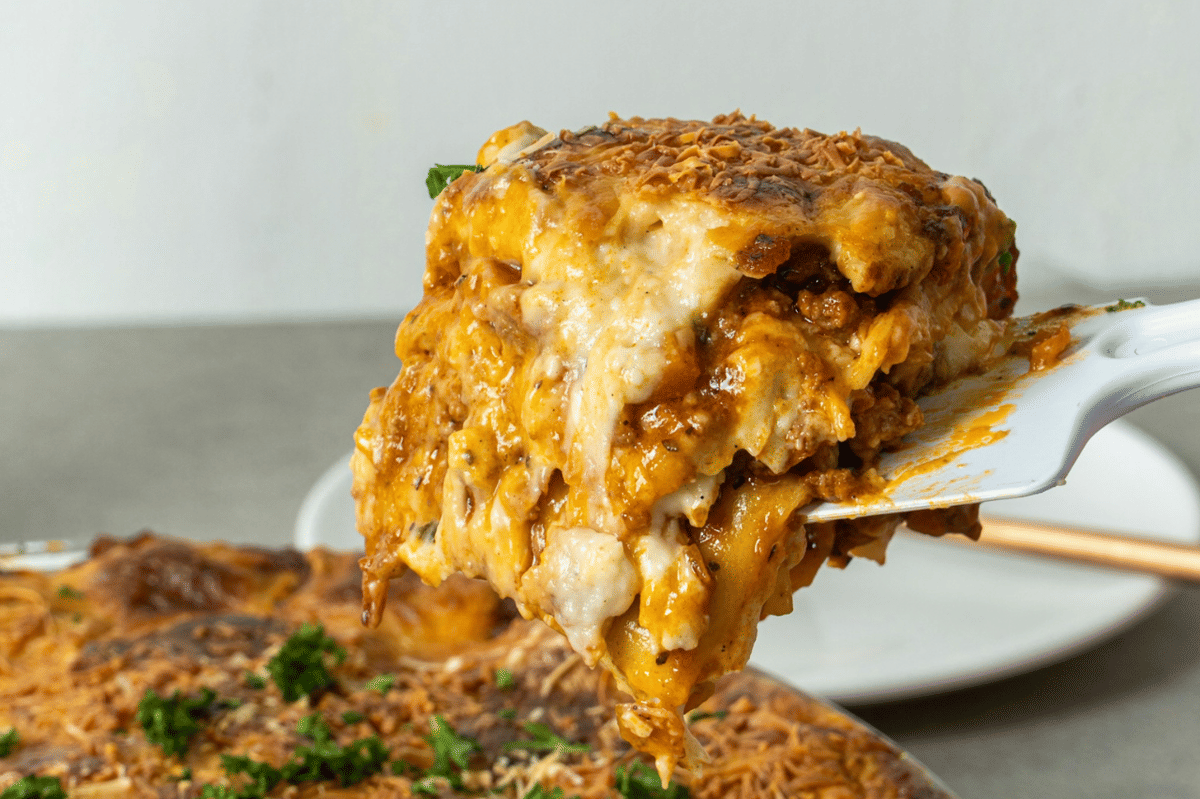 Seporsi cheesy cottage pie berlapis kentang tumbuk keemasan dan saus daging, disajikan hangat dalam wadah panggang.