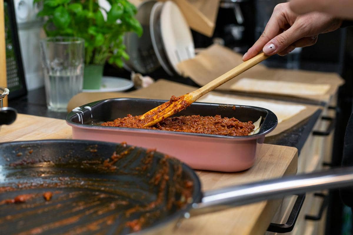 Cottage pie berlapis kentang tumbuk dengan keju leleh, disajikan dalam wadah panggang di atas meja.