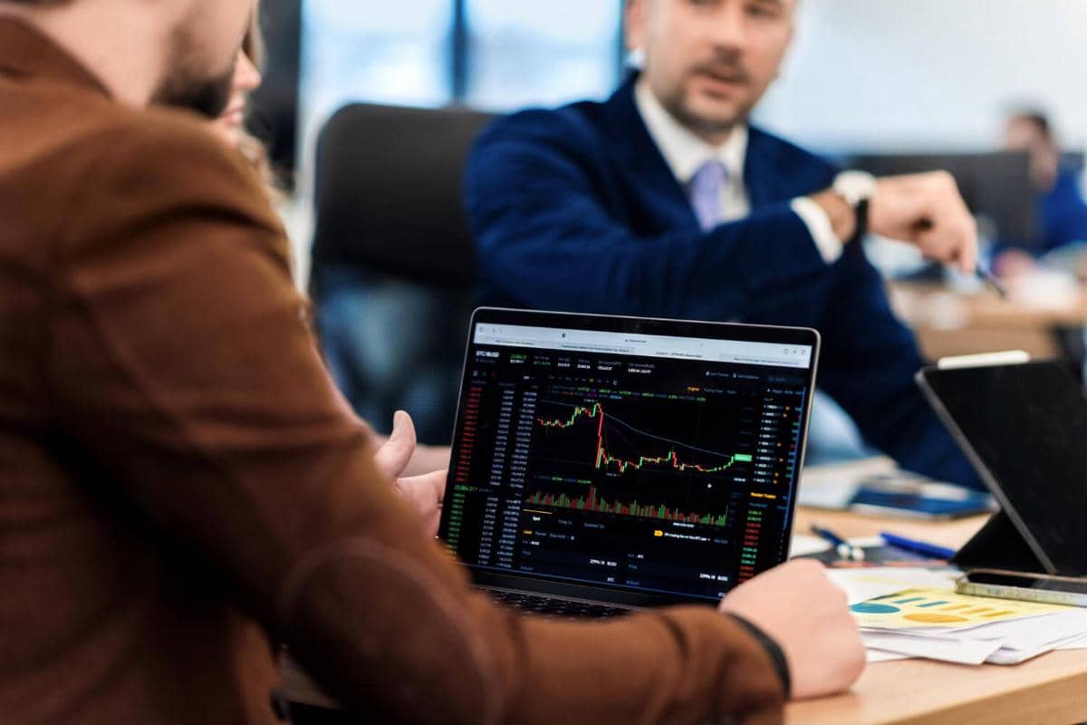 Ilustrasi investor berdiskusi dalam rapat sambil menganalisis data pasar saham dan peluang investasi.
