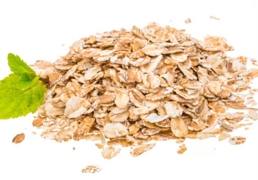 Semangkuk oatmeal hangat disajikan dalam mangkuk di atas meja kayu dengan sendok sebagai pelengkap sarapan.