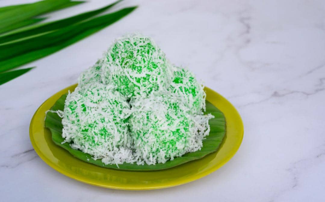 Ilustrasi klepon oatmeal pandan berwarna hijau dengan taburan kelapa parut sebagai sajian camilan tradisional.