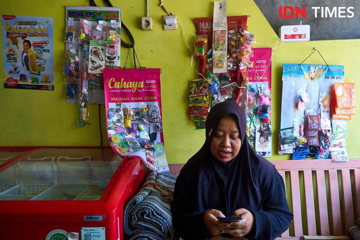 Rivachul Wahidah mengakes aplikasi layanan keuangan digital melalui ponsel di dekat perangkat jaringan Internet Rakyat (IRA) yang terpasang 