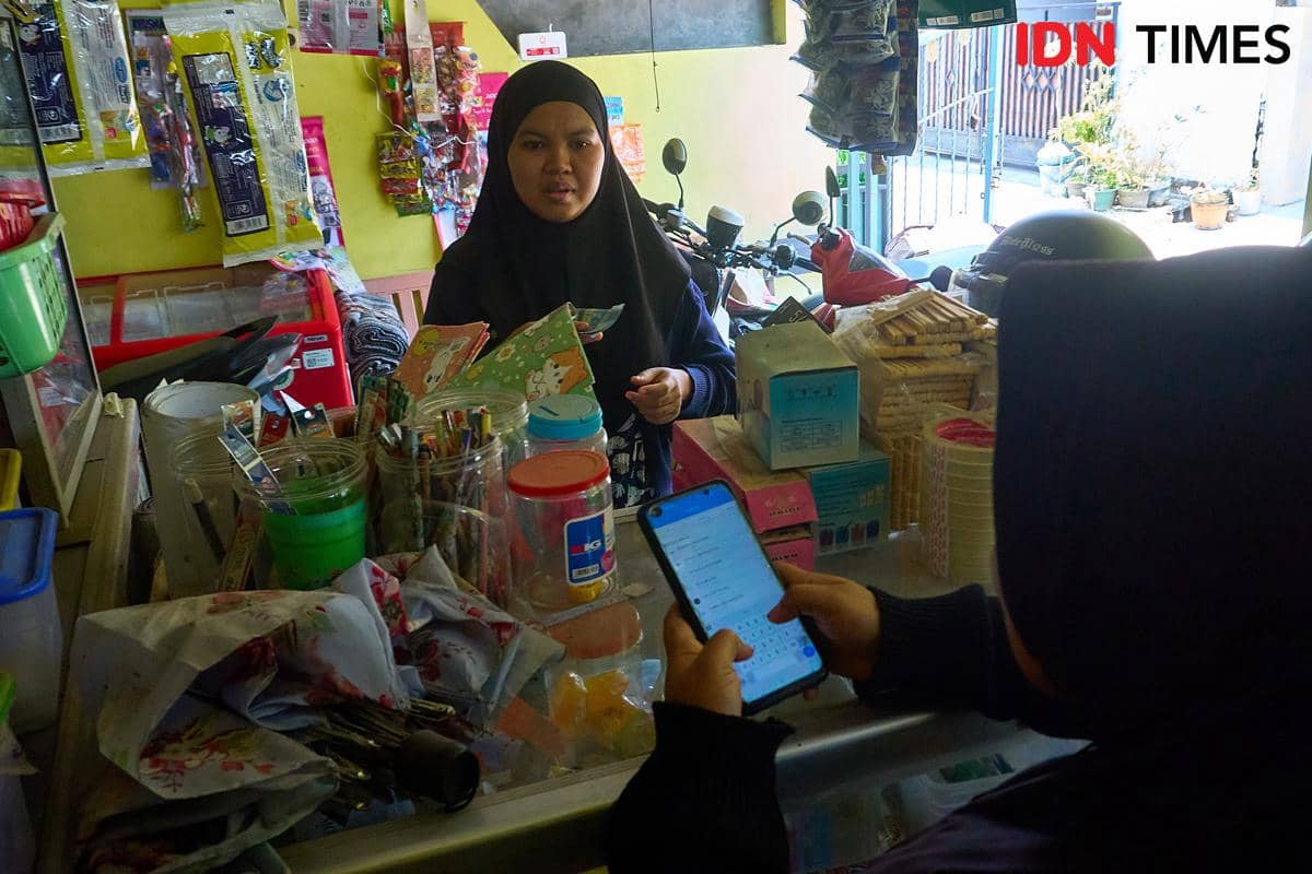 Seorang pelanggan menunggu Rivachul Wahidah memproses pengisian saldo dompet digital di Warung Al Barokah, Kabupaten Demak, Jawa Tengah, Jum