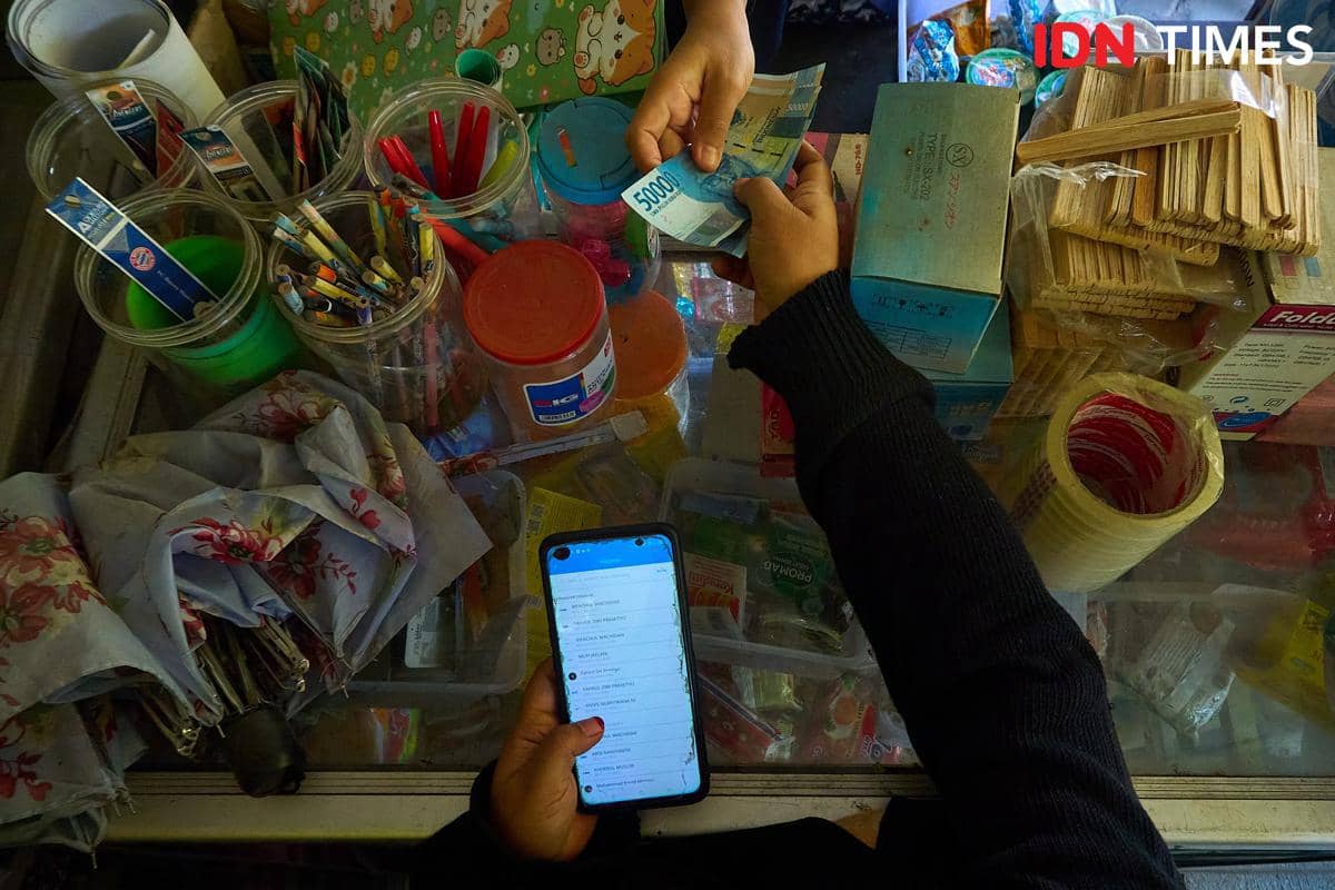 Uang tunai berpindah tangan di atas etalase Warung Al Barokah, Demak, Jawa Tengah, Jumat (16/10/2026). Selain melayani jual beli barang kebu