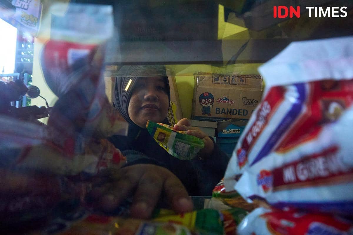 Rivachul Wahidah menata barang dagangan di etalase Warung Al Barokah, Demak, Jawa Tengah, Jumat (16/10/2026). Di warung tersebut, ia memaduk