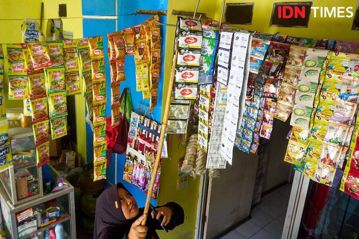 Rivachul Wahidah mengambil barang dari deretan produk yang menggantung di Warung Al Barokah, Demak, Jawa Tengah, Jumat (16/10/2026). Makanan
