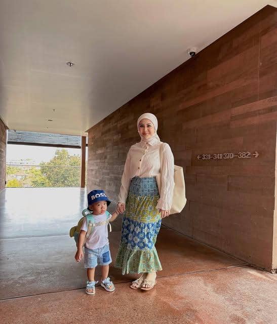 Kesha Ratuliu berpose dengan gaya OOTD pantai di tepi laut, mengenakan busana kasual bernuansa cerah.