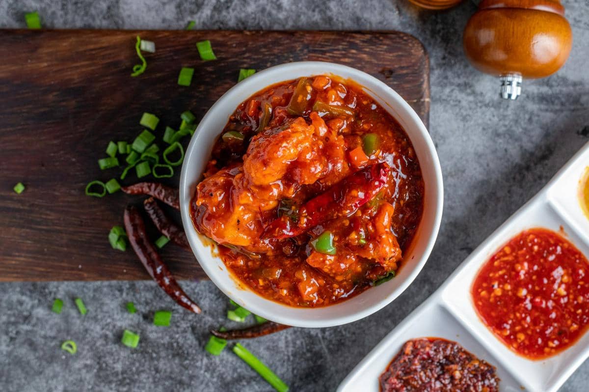 Semangkuk chicken paprikash dengan potongan ayam dalam saus paprika kental, disajikan bersama nasi dan taburan peterseli.
