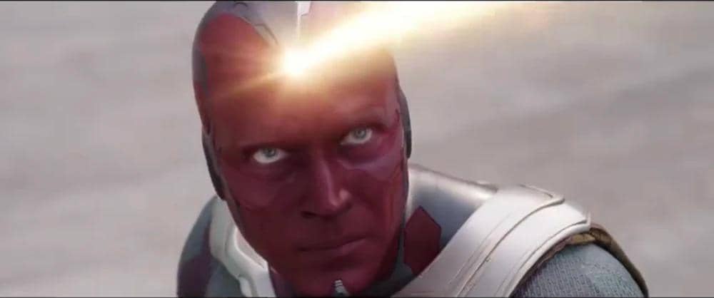 Vision berwajah merah mengenakan setelan abu-abu dan jubah cokelat dalam adegan Captain America: Civil War.