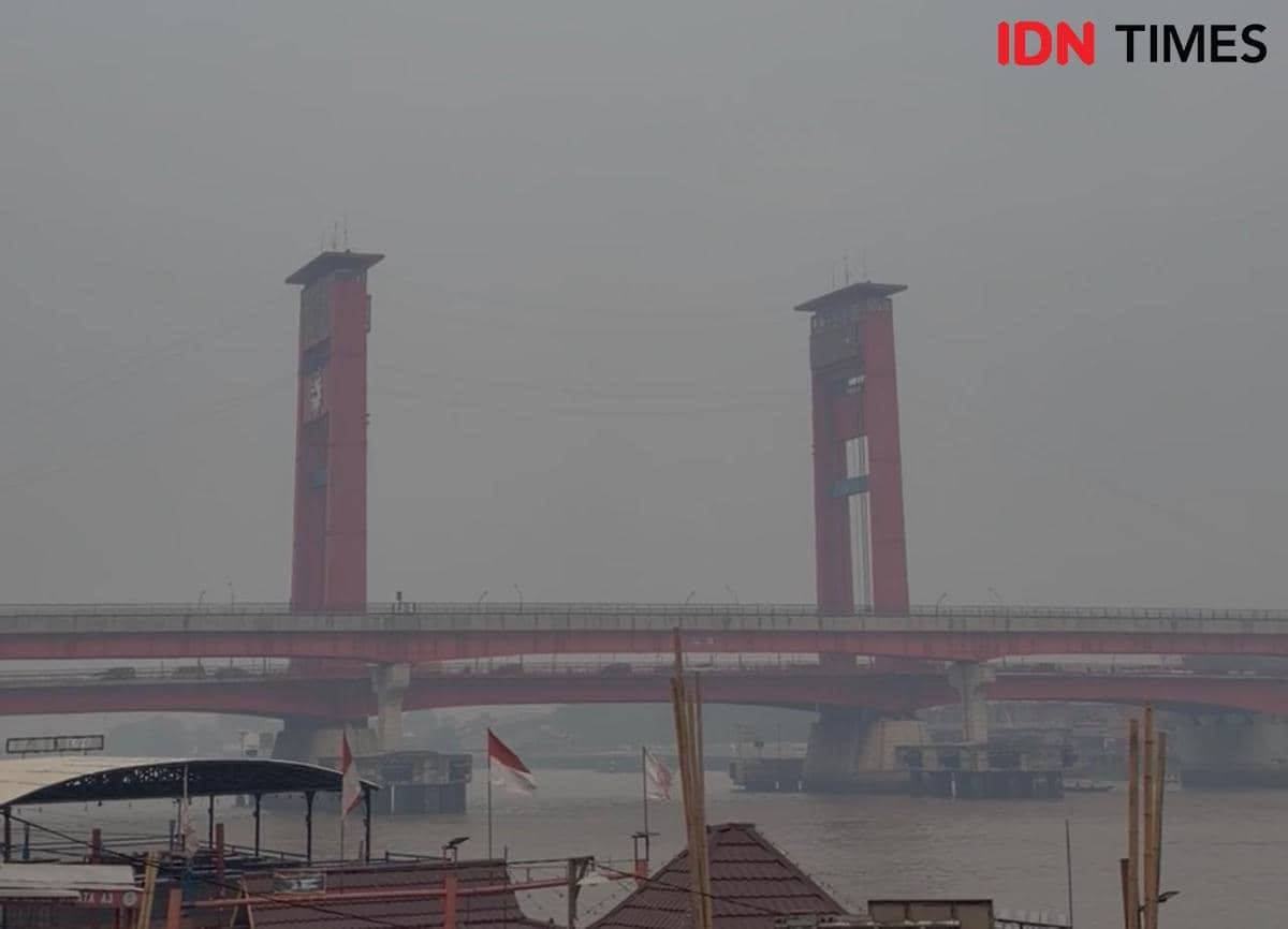 Kabut asap menyelimuti kawasan Palembang pada pagi hari, mengurangi jarak pandang dan membuat suasana tampak berkabut.