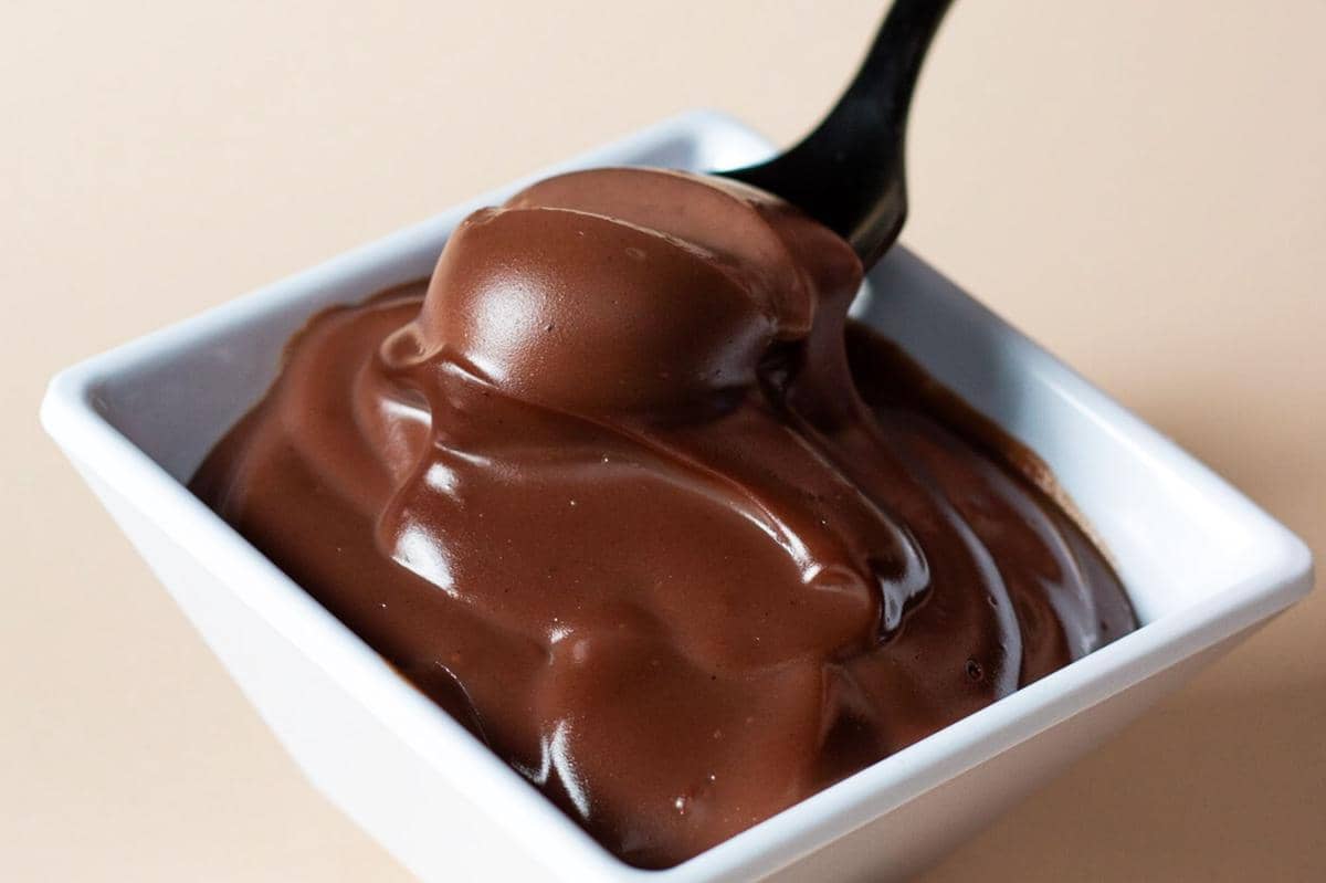 Lelehan cokelat berwarna cokelat tua dengan tekstur mengilap membentuk permukaan cair yang lembut dan kental.