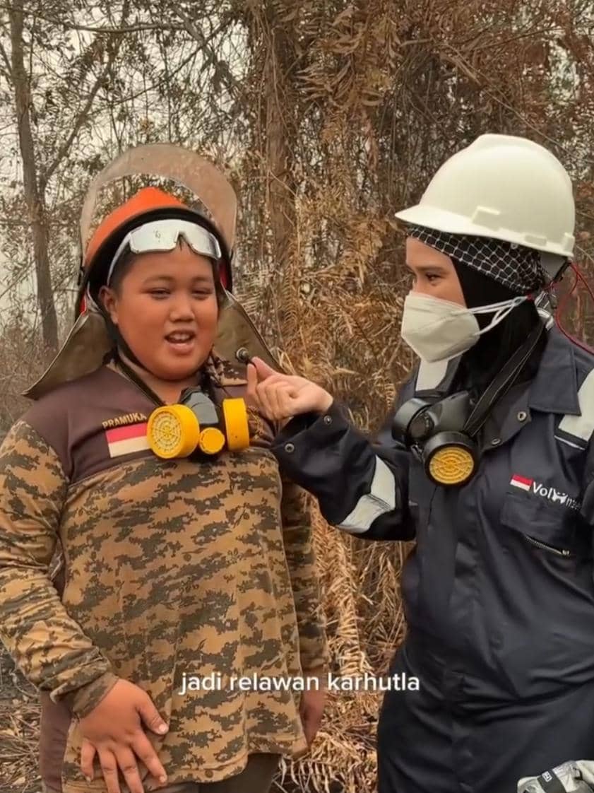 Seorang relawan karhutla mengenakan pakaian lapangan berdiri di area terdampak kebakaran hutan dan lahan.