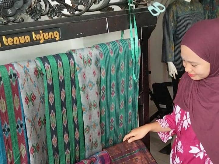Seorang pegawai merapikan kain tenun yang dipajang di Centra Tenun Tajung, kawasan Tuan Kentang, Palembang.