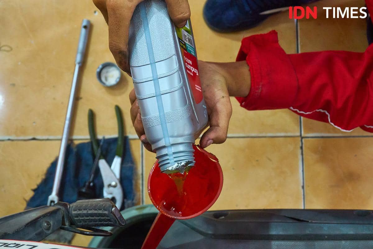Seorang siswa menuangkan pelumas Pertamina Enduro baru saat menangani servis rutin sepeda motor pelanggan di bengkel Karya Speed, SMK Harapa