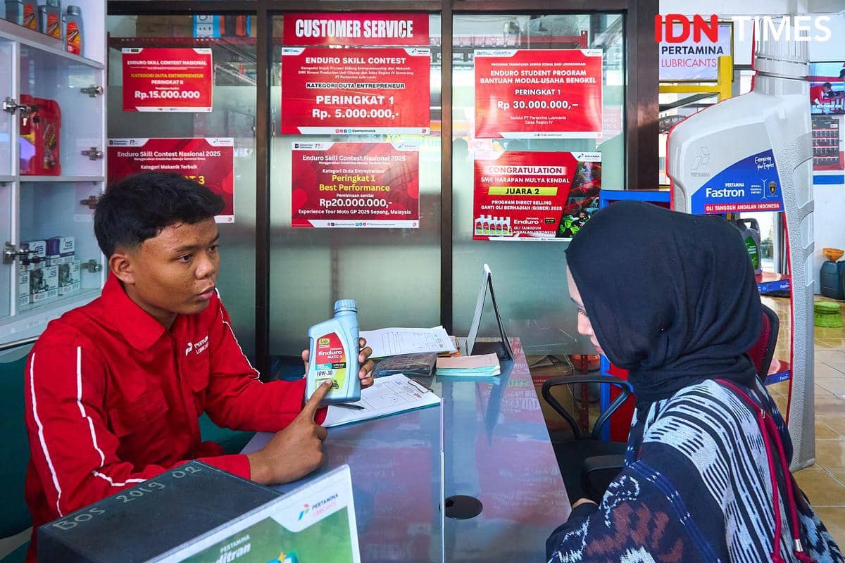 Seorang siswa mencatat keluhan pelanggan pada Surat Perintah Kerja (SPK) di meja penerimaan (front desk) bengkel Karya Speed, SMK Harapan Mu