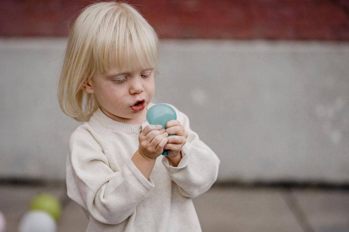 Seorang anak bermain dengan mainan squishy berbentuk dumpling yang dipegang di kedua tangan kecilnya.