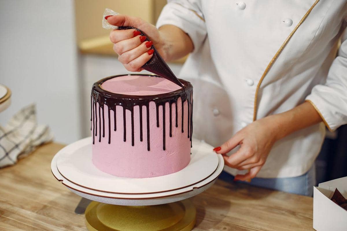 ilustrasi seorang koki profesional menambahkan lapisan cokelat leleh pada kue di dapur