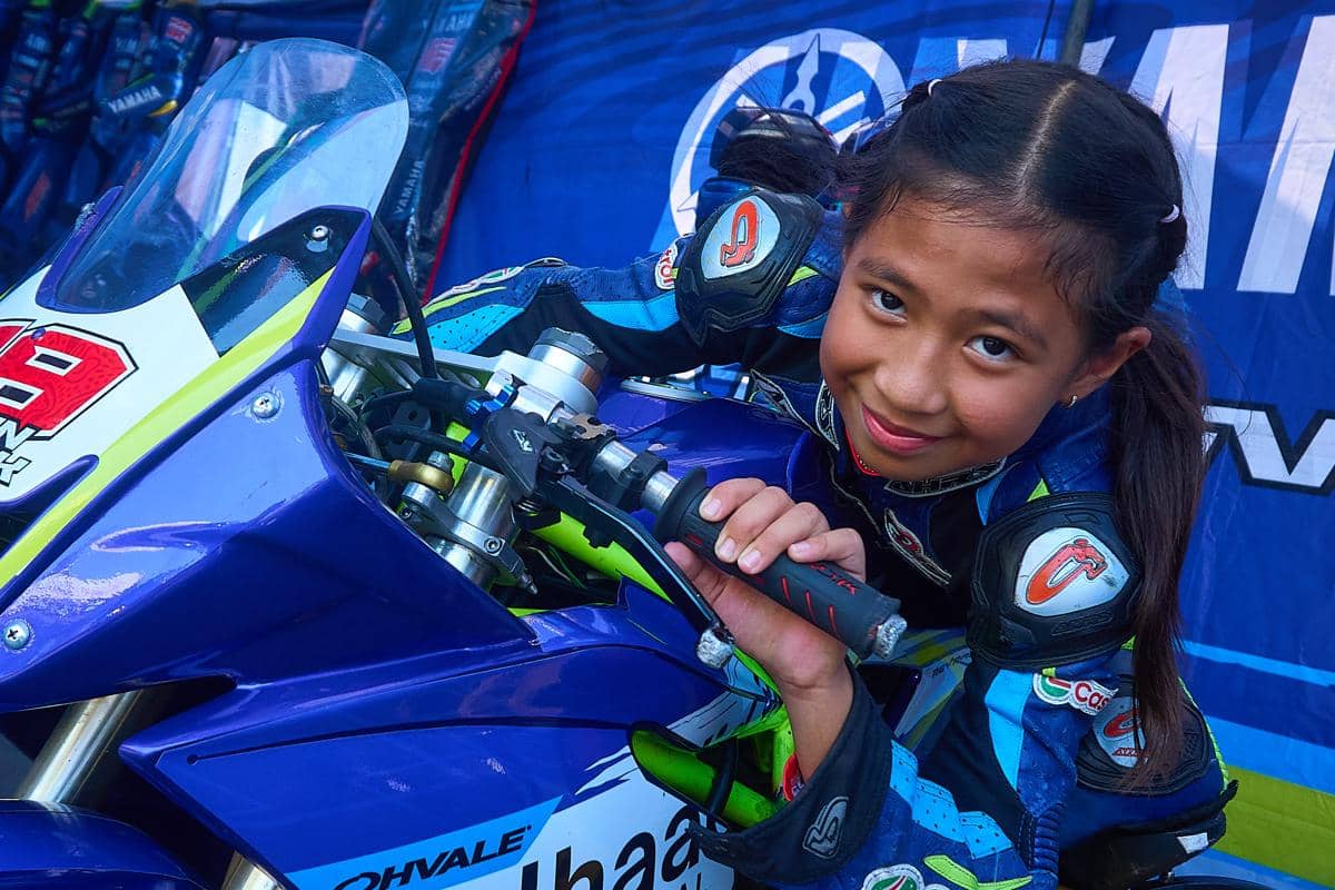 Pembalap usia dini asal Bandung, Jawa Barat, Hanin Dhiya Humaira (10), menatap kamera sambil memegang setang sepeda motor balapnya di area p