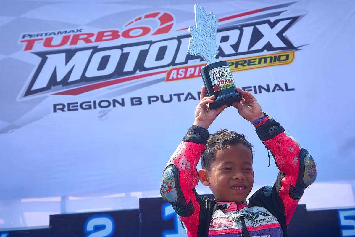 Pembalap cilik Ariendra Pandhu tersenyum lepas sambil mengangkat trofi juara kelas Pocket Bike di area podium Final Pertamax Turbo MotoPrix 
