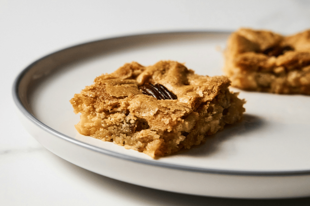Potongan pumpkin pie bars berlapis isian labu oranye dan remah kue, tersaji di atas piring sebagai ilustrasi makanan.