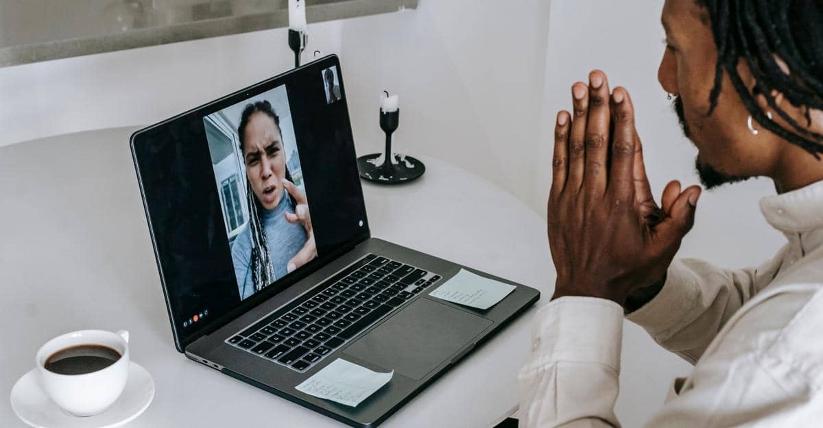 pria menangkupkan kedua tangan di depan layar laptop saat panggilan video